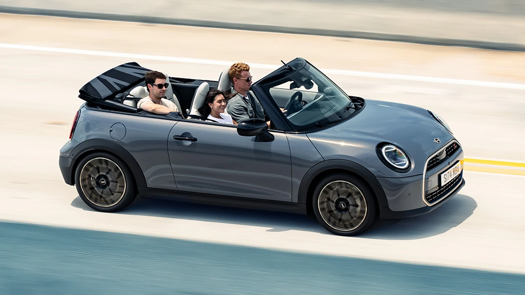 MINI Cooper Cabrio garé devant un paysage urbain, capote ouverte